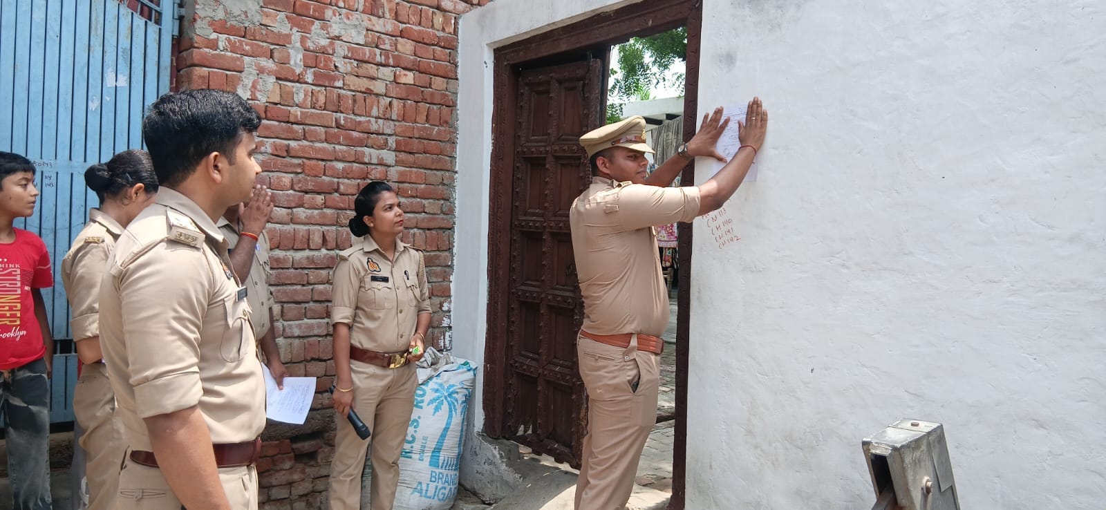 गढ़ के गांव नानपुर में फरार आरोपियों के घर नोटिस चस्पा करती पुलिस। स्रोत : पुलिस