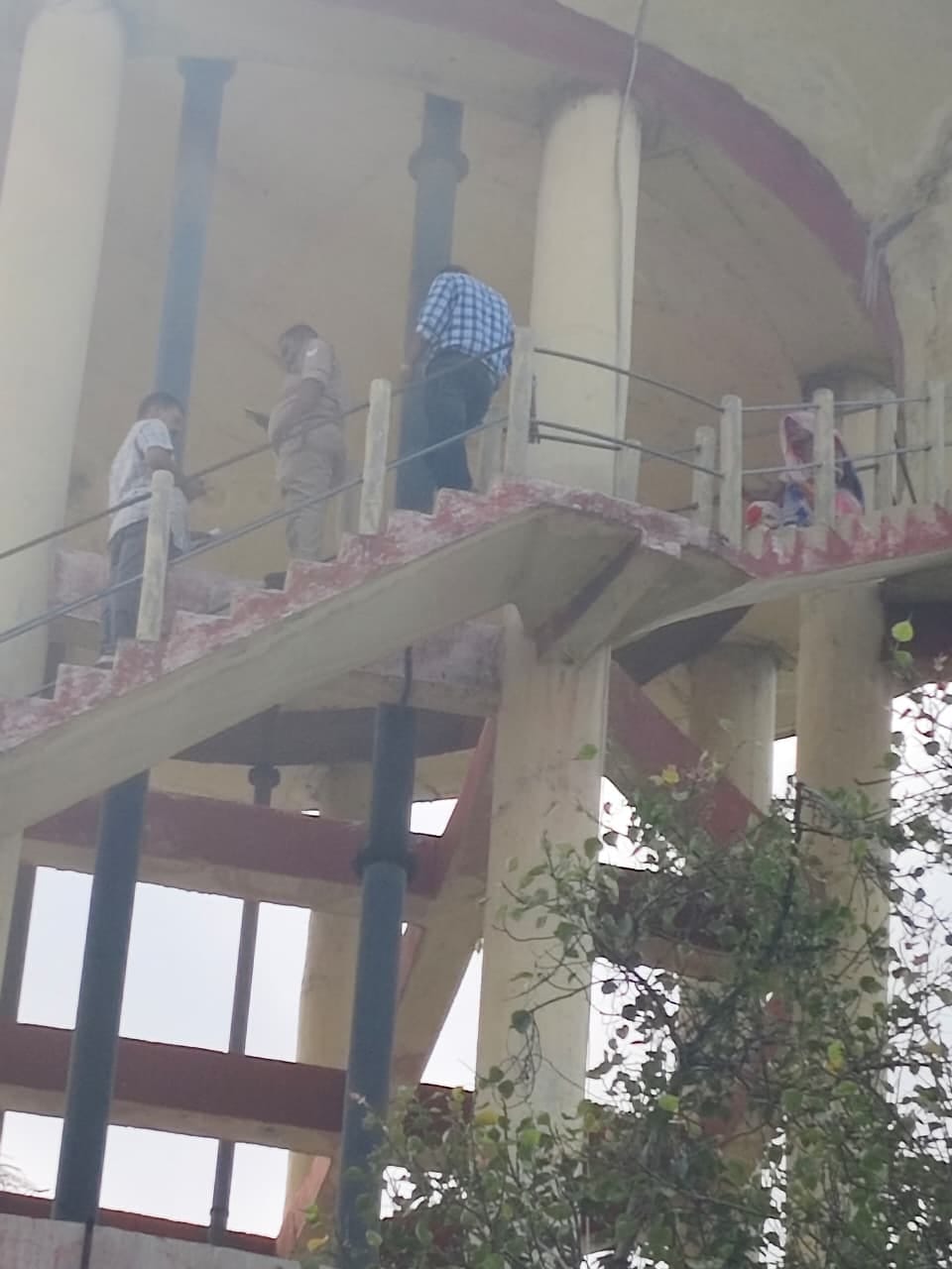 Woman climbs water tank in protest against land encroachment.