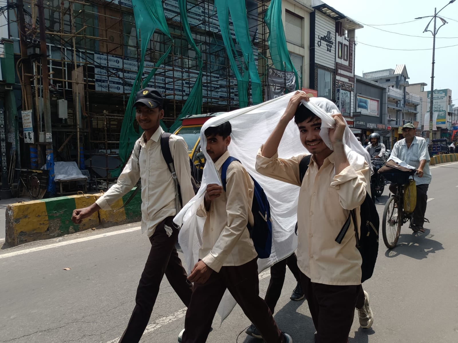 भीषण गर्मी में बचाव के लिए सिर पर चादर ओढकर जाते किसान इंटर कॉलेज के छात्र। संवाद