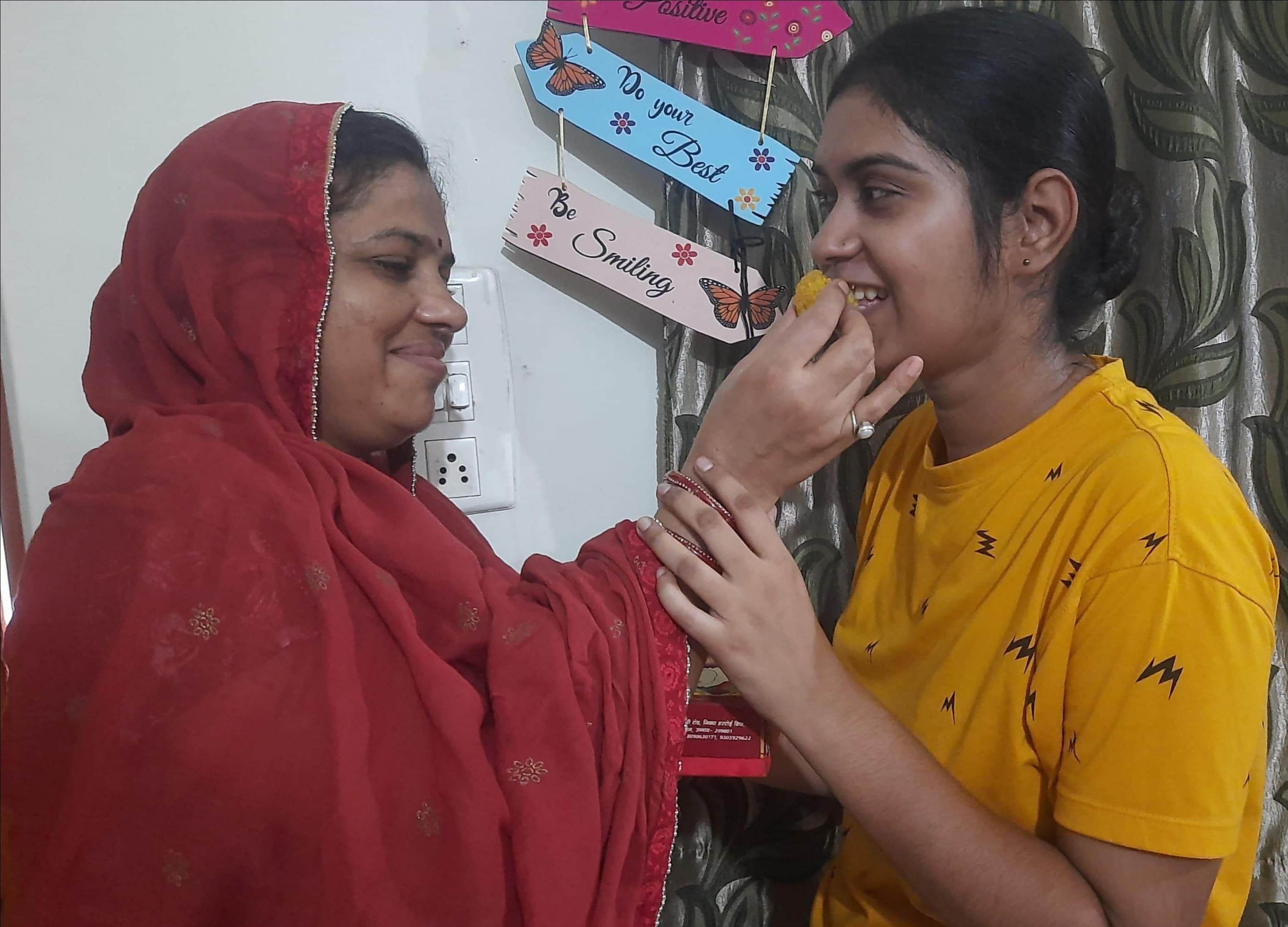 फोटो-13- दरोगा बनीं बेटी आकांक्षा को मिठाई खिलातीं मां विमला शुक्ला। स्रोत: परिजन