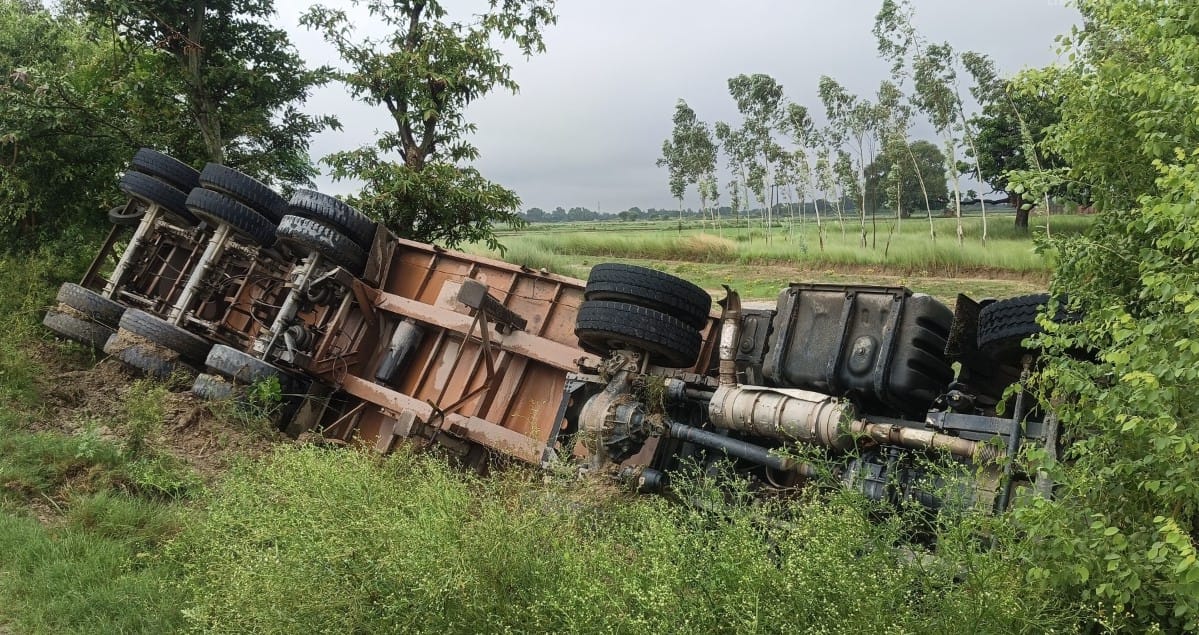 Trailer loaded with gravel overturns in a ditch while trying to avoid a motorcyclist.