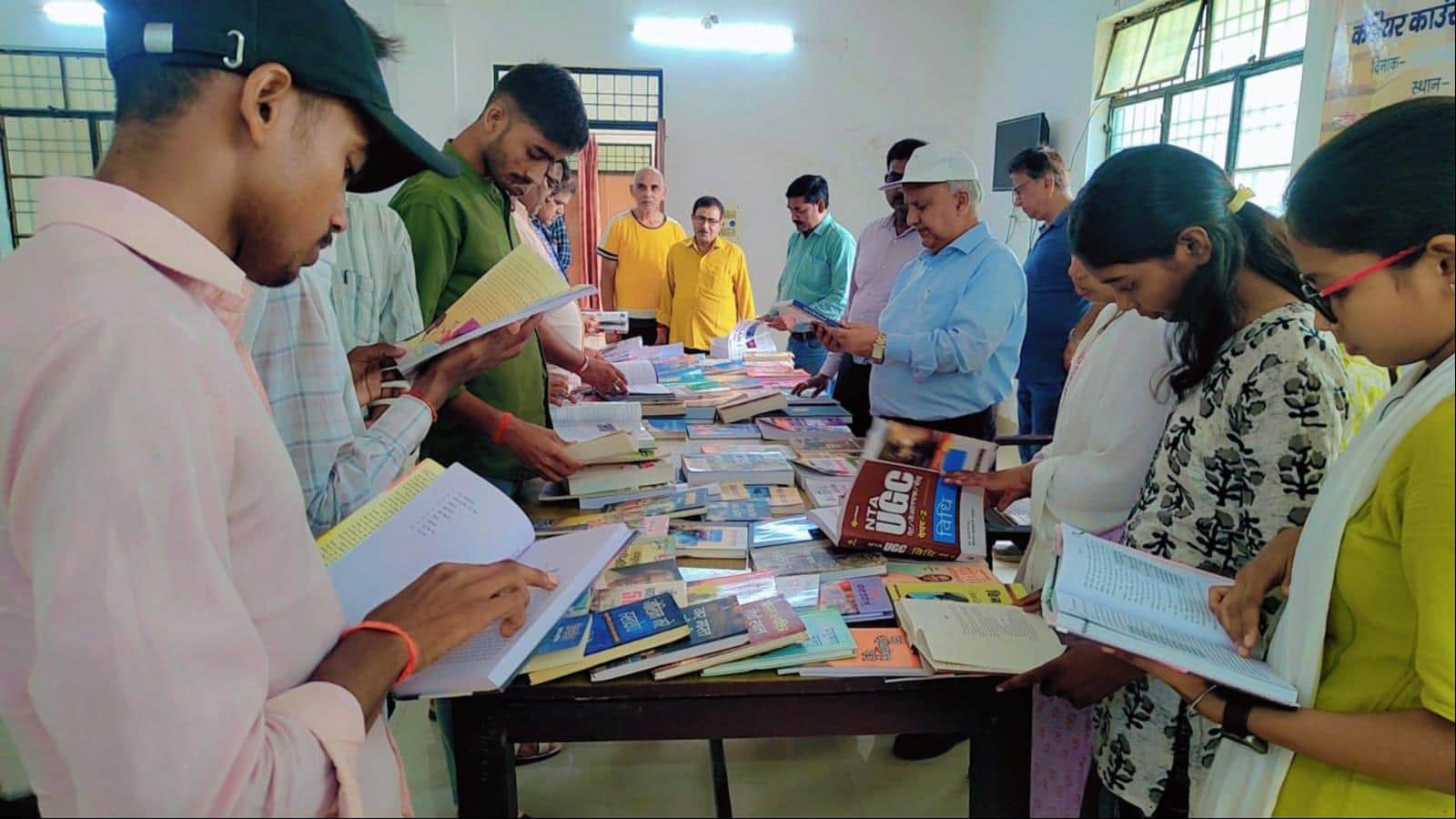 राजकीय जिला पुस्तकालय में आयोजित पुस्तक़ मेले में किताबों का अवलोकन करते अतिथि और विद्यार्थी।