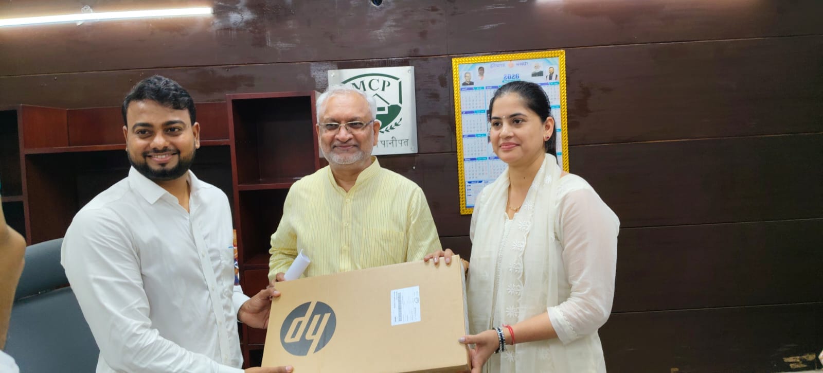 पार्षद अशोक कटारिया को लैपटॉप देते मेयर कोमल सैनी। स्रोत : सोशल मीडिया