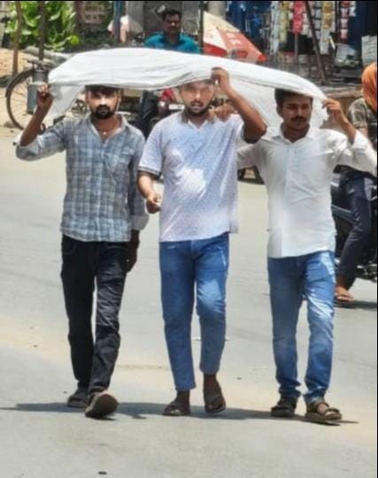 धूप से बचाव के लिए एक ही गमछा ओढ़कर अपने गंतव्य को जाते युवक।संवाद