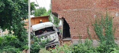 Dumper crashes into house while trying to avoid a container; pillar and gate collapse.