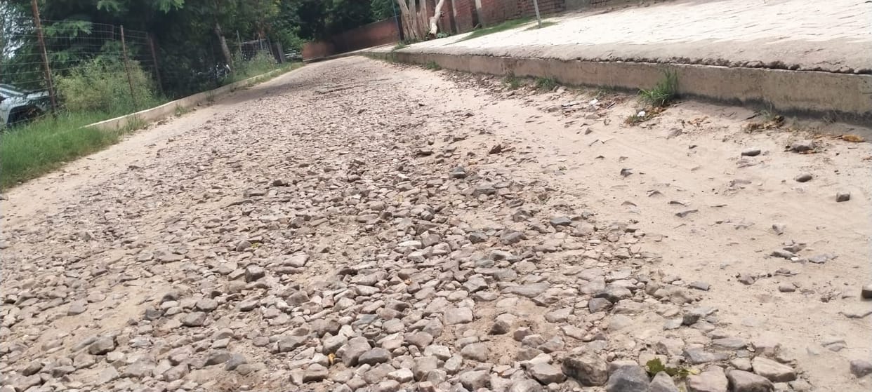Bus stand access road riddled with potholes; passengers call for repairs.