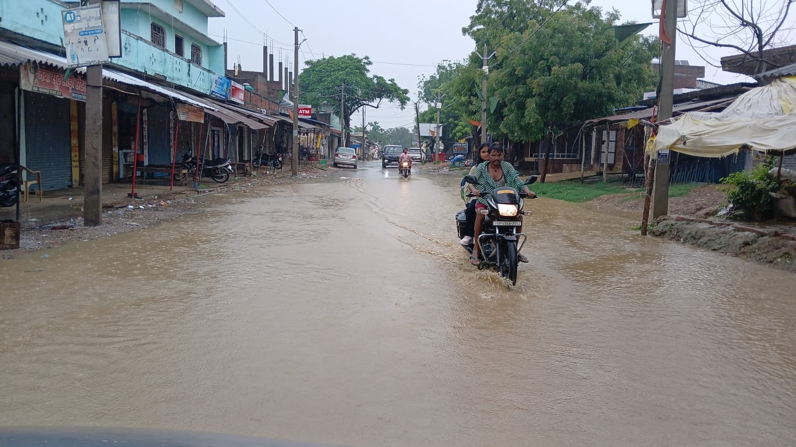 सम्मनपुर बाजार में बारिश के बाद जलभराव के बीच गुजरते राहगीर। संवाद