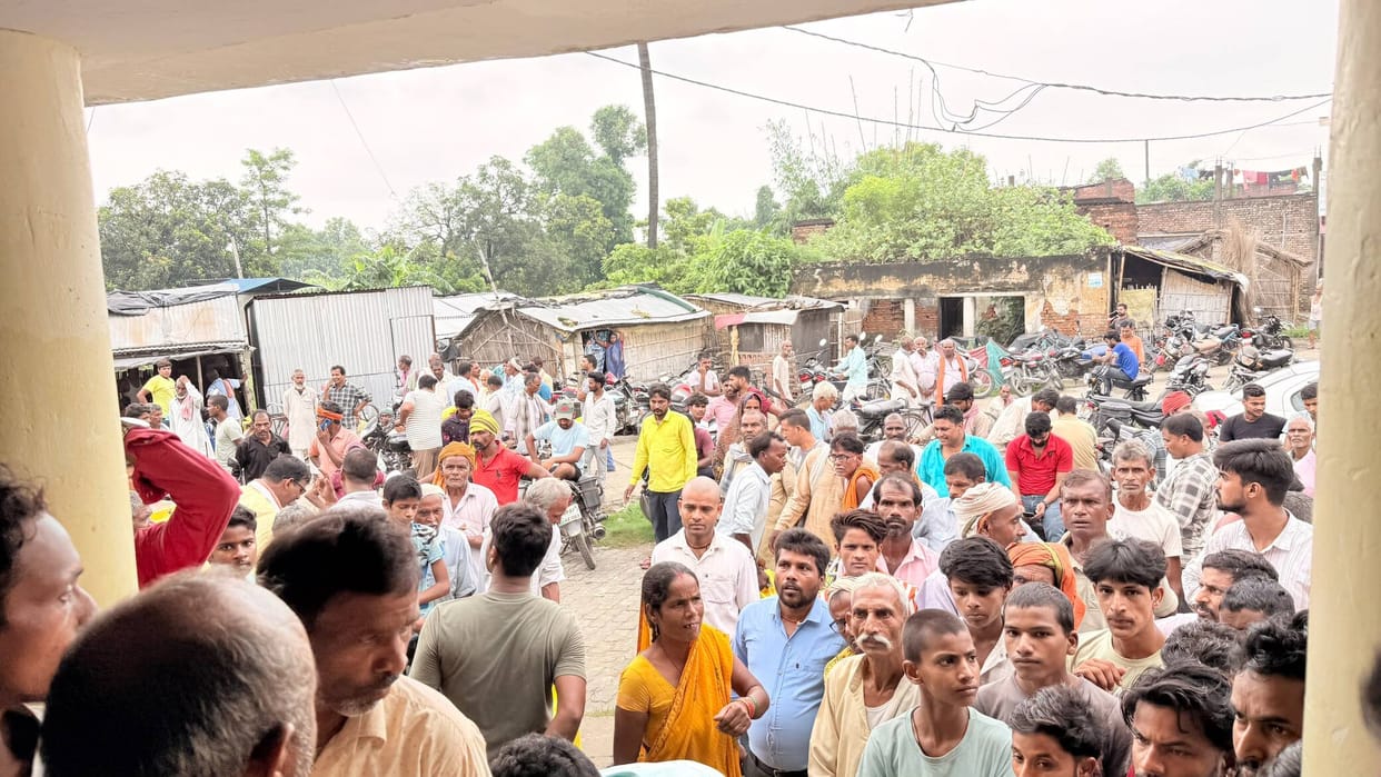 Crowd of farmers swarms for fertilizer amidst the rain.