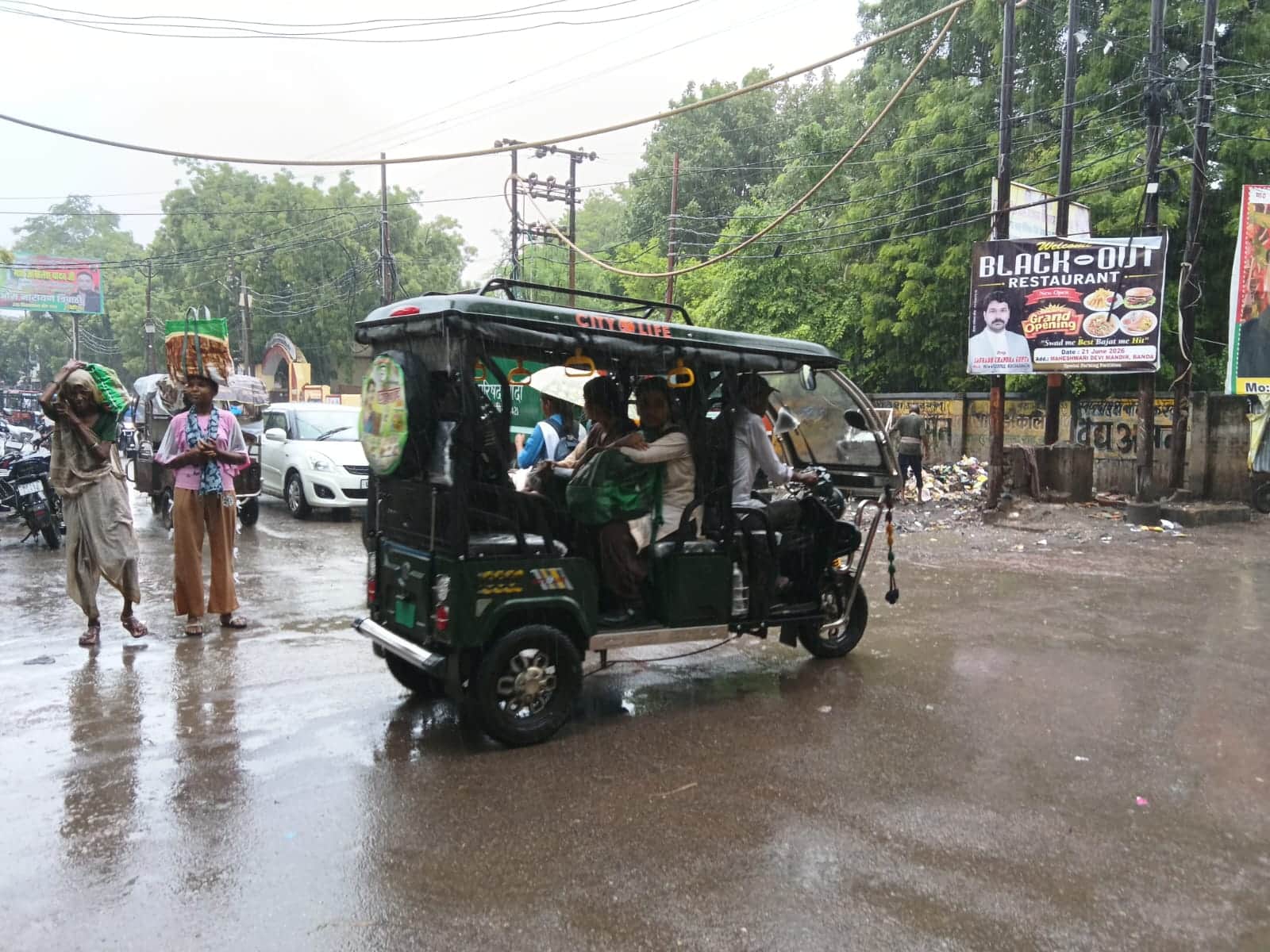 फाेटो-8- बांदा शहर में बारिश के बीच ई रिक्शा से जाते स्कूली बच्चे। संवाद