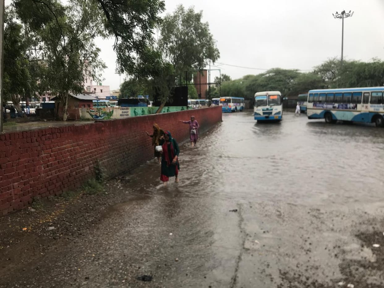 Bus stand submerged in rain; passengers face increased difficulties.