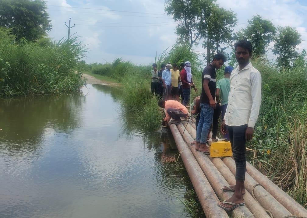 Young men built an improvised culvert by joining electricity poles together.