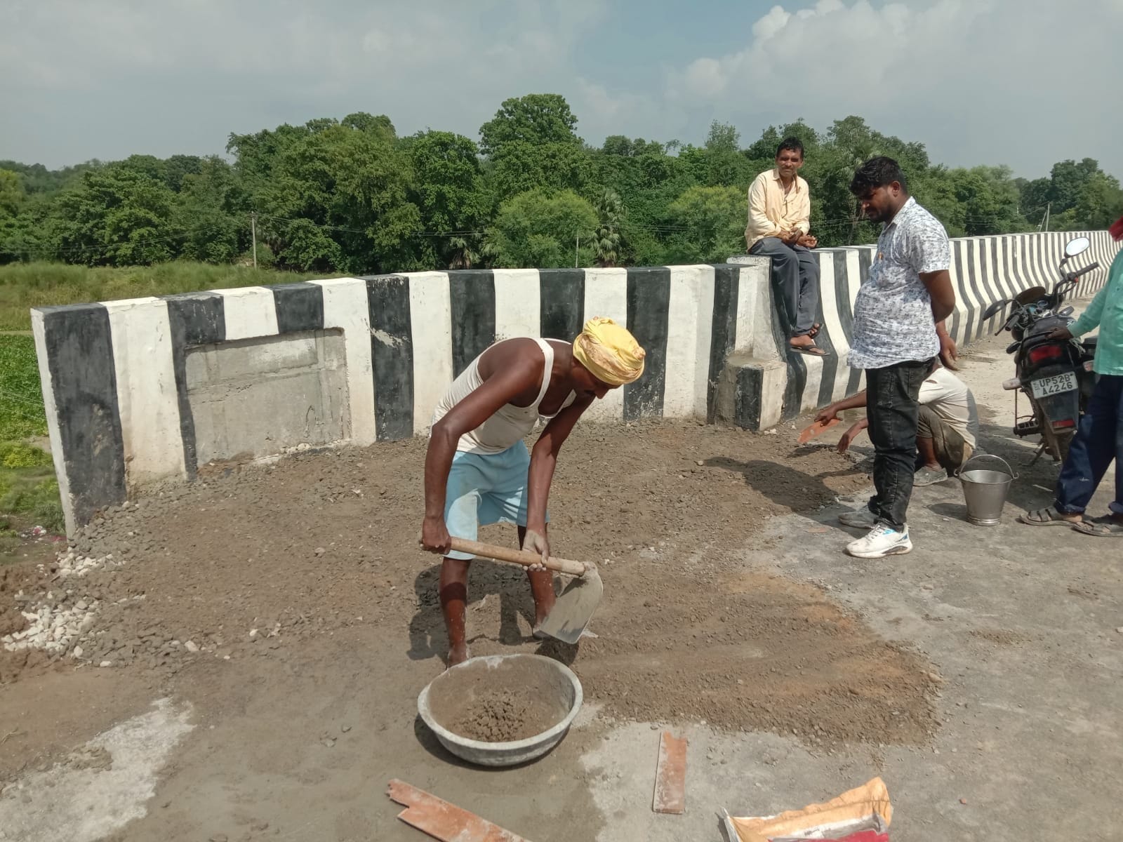 नरही में बारिश धंसे मगई नदी पर बनी पुलिया के एप्रोच मार्ग का मरम्मत करते मजदूर।संवाद