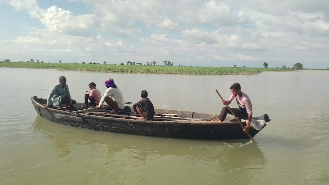 नाव से खेतिहर इलाके में आवागमन करते बोझवा मटहिया के लोग। संवाद