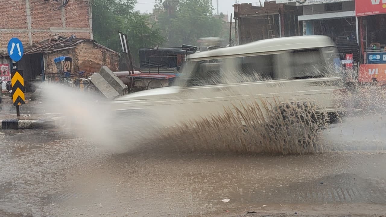 फोरलेन सड़क पर लगे बारिश के पानी होकर गुजरता बोलेरो। संवाद