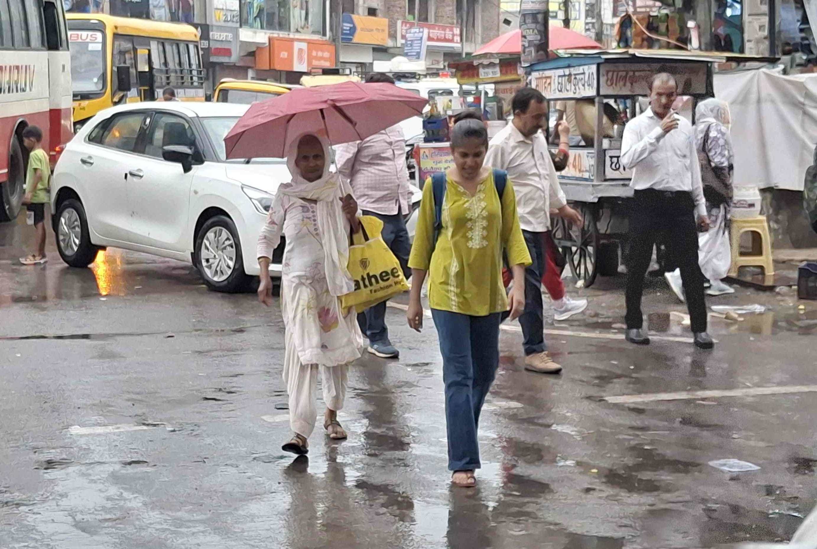 -फोटो 87 : बारिश के बीच छाता लेकर गंतव्य की ओर जाती बुजुर्ग महिला व युवती। संवाद