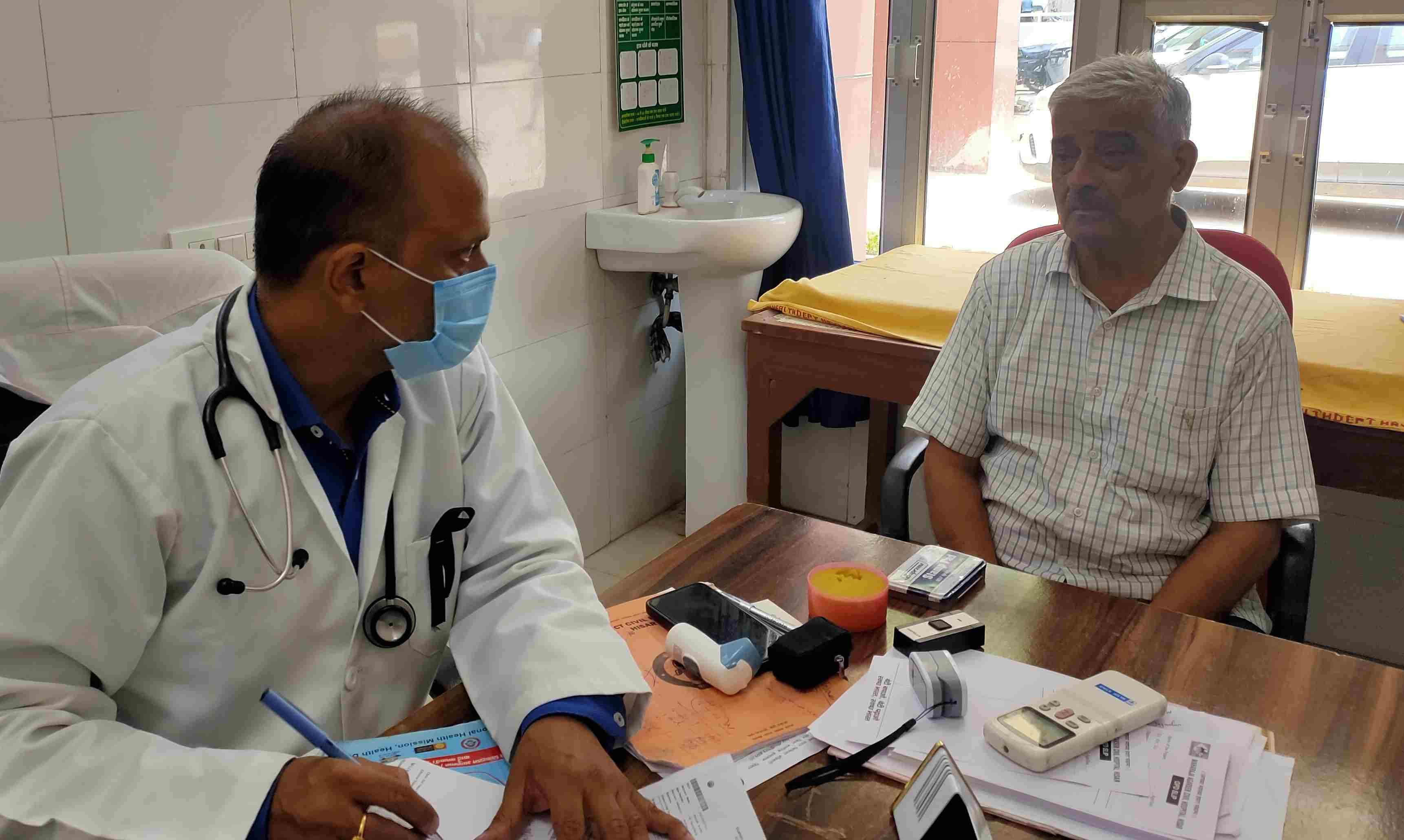 जिला नागरिक अस्पताल में काले बिल्ले लगाकर मरीजों को देखता चिकित्सक। 