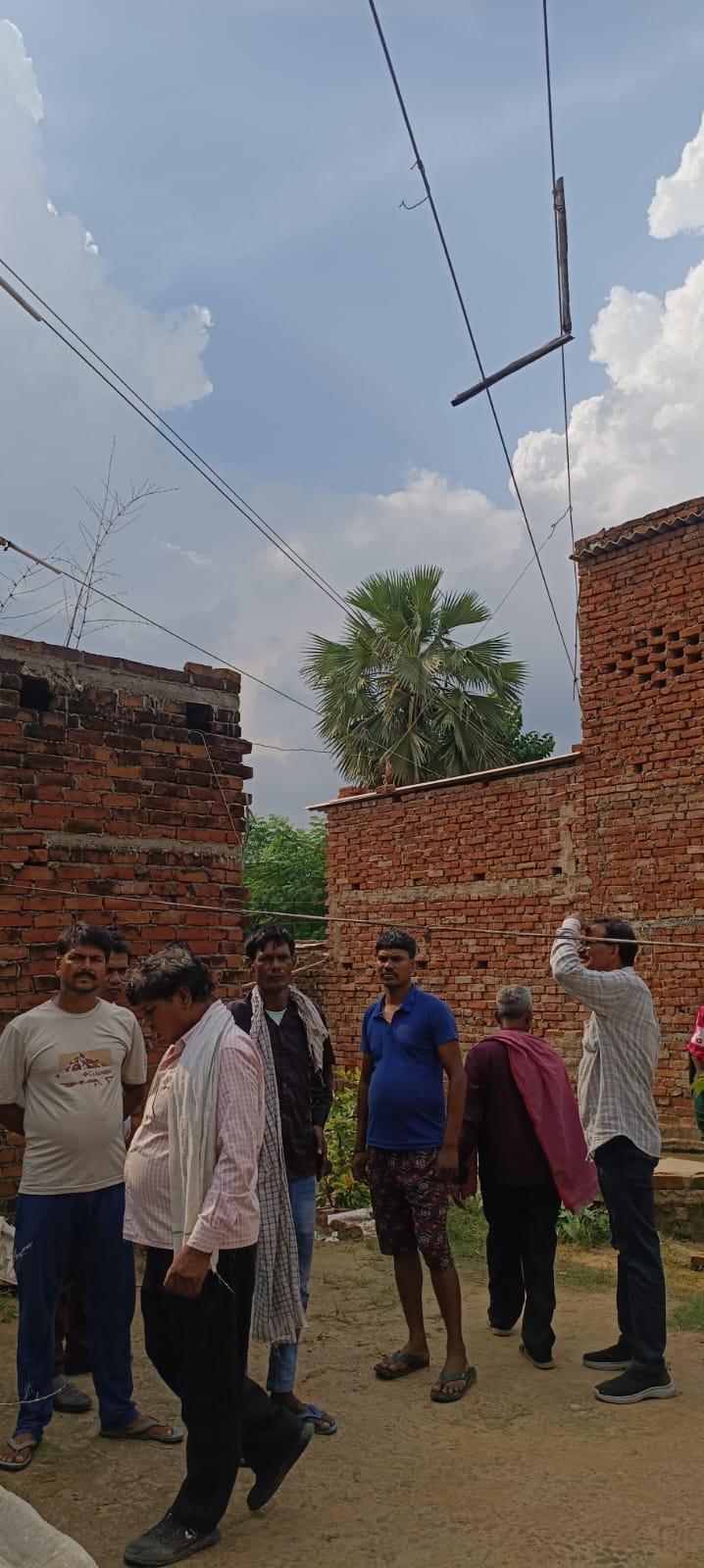 कोपागंज थाना के फैजुल्लाहपुर में हरेंद्र के घर के ऊपर से गुजरा हाईटेंशन तार नीचे खड़े लोग। संवा