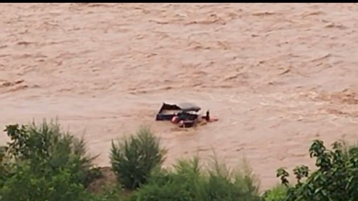 Two people stranded on a tractor in the middle of the Gaj Khad after the rain.