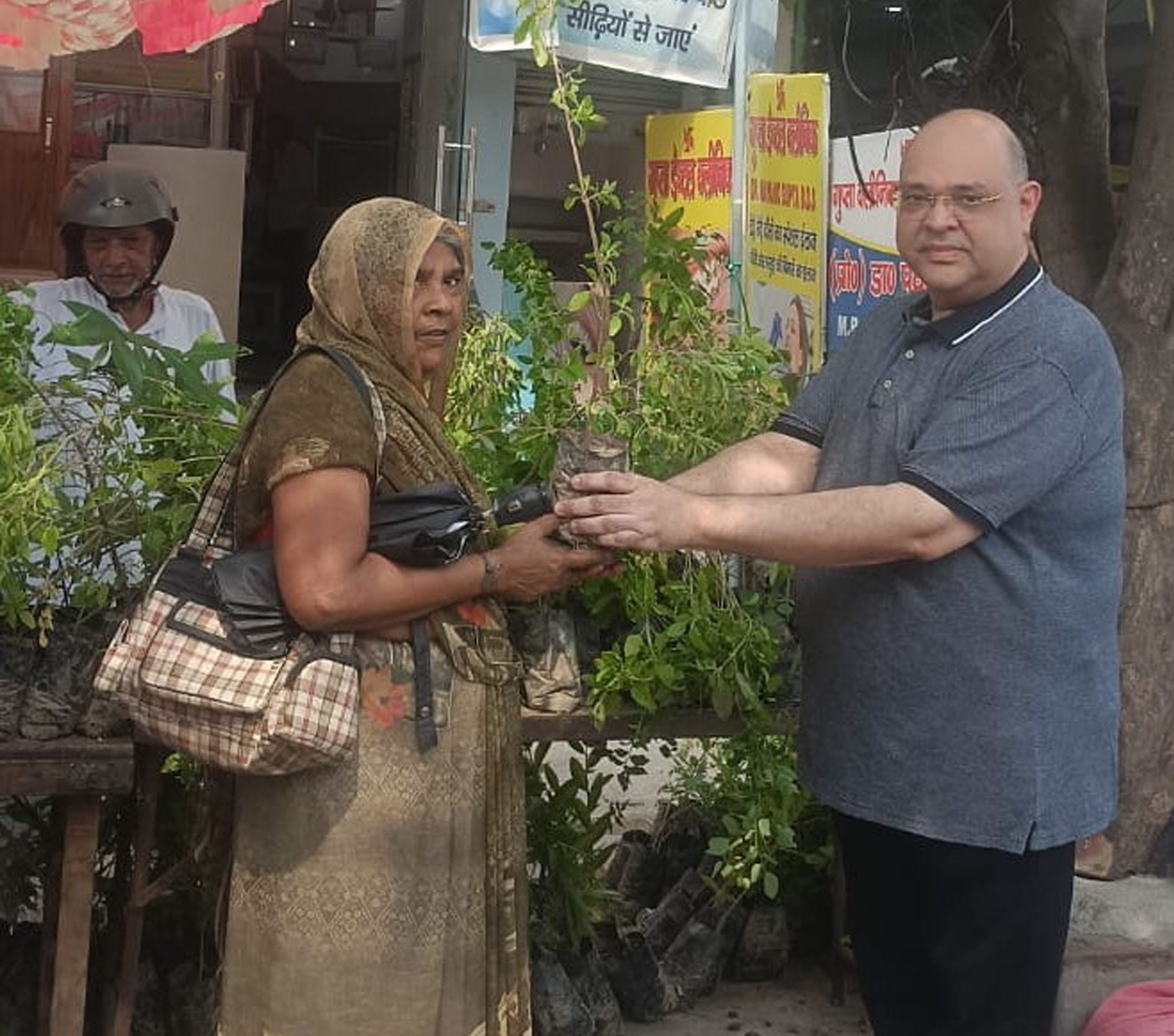 फोटो-61: रेलवे रोड पर महिला को पौधा भेंट करते  डॉ. मयंक गुप्ता। स्रोत स्वयं