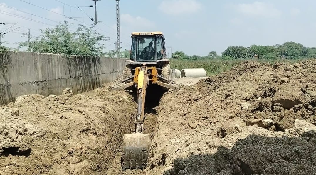 जंघई फ्लाईओवर के नीचे जलनिकासी की पाइप के लिए खुदाई करता जेसीबी। स्रोत-संवाद