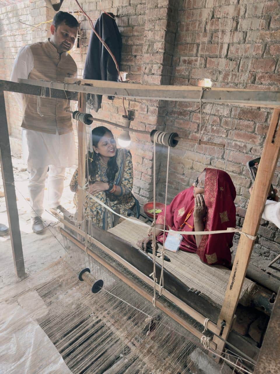 कुर्ते के कपड़े की बुनाई होते देखते लोग।  स्वयं