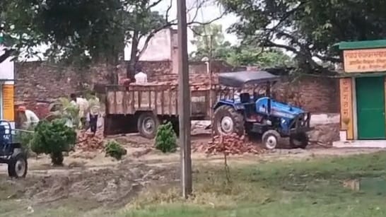 विद्यालय से जर्जर भवन की ईंट उठाते मजदूर और ट्रैक्टर ट्रॉली।संवाद