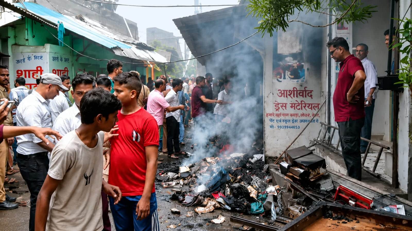 फोटो-1-दुकान के बाहर पड़ा, आग से जला सामान और जमा लोग। संवाद