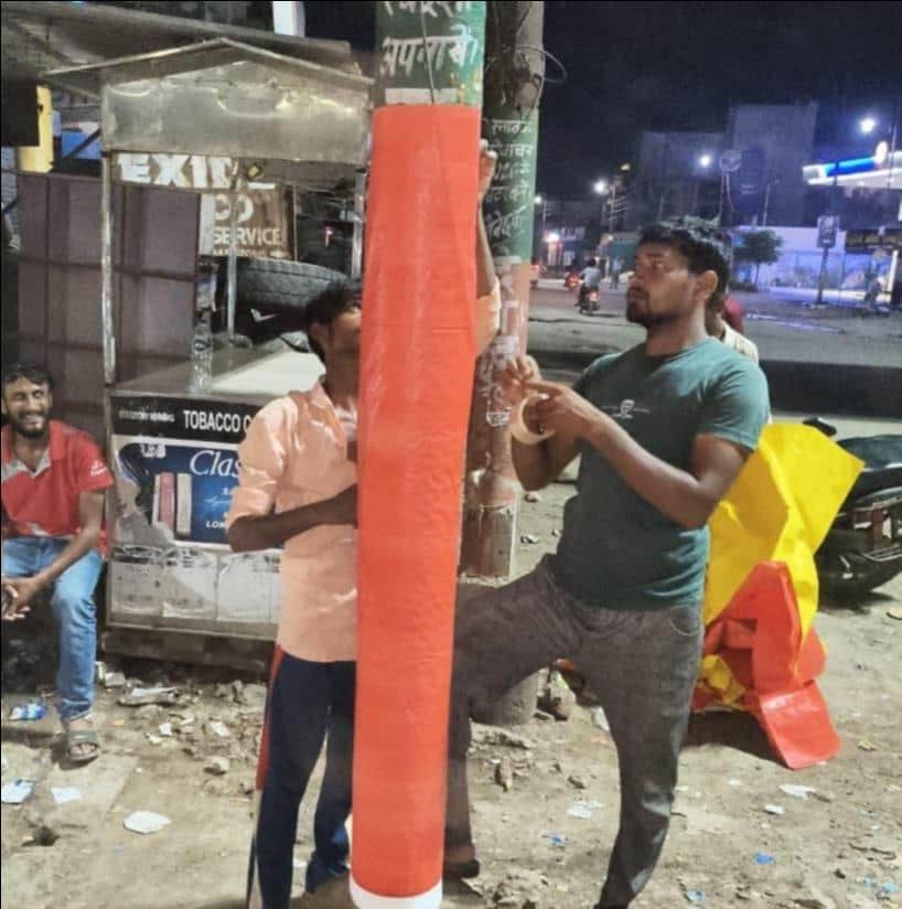 रॉबर्ट्सगंज के सिविल लाइंस रोड पर बिजली के खंभे पर तिरपाल बांधते कर्मचारी। स्वयं