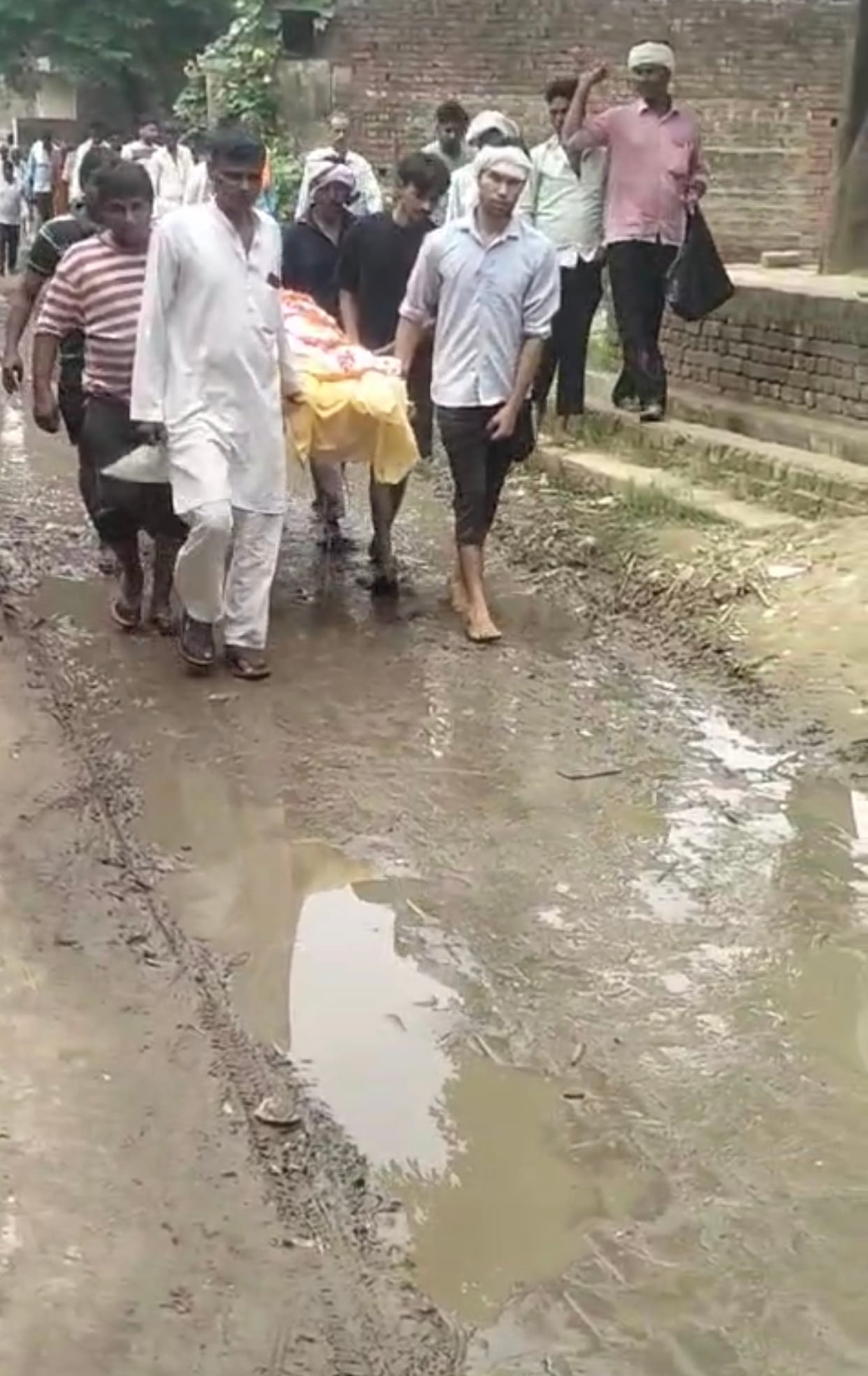 The elderly person's final journey proceeded along a muddy path.