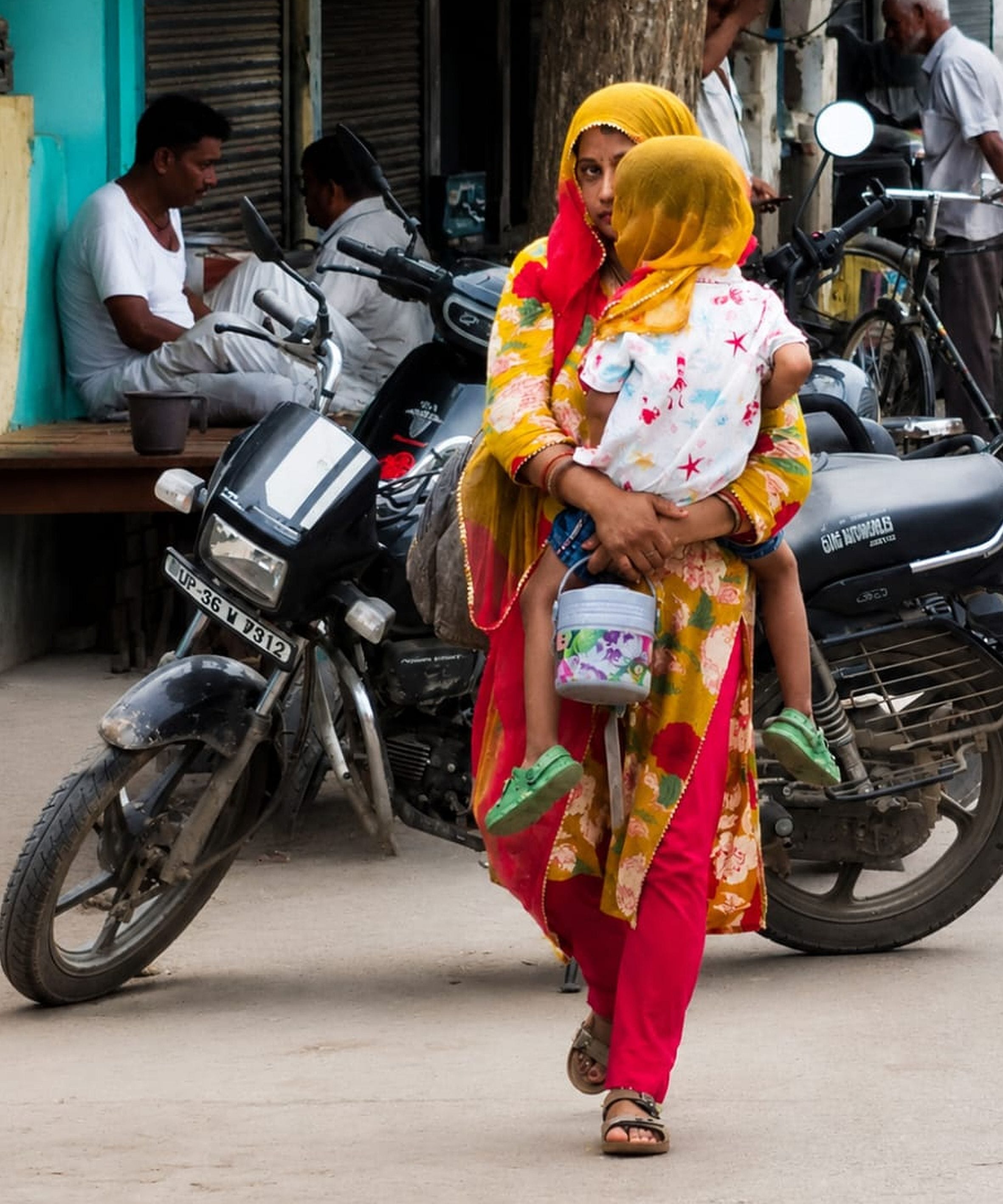  अमेठी शहर में धूप से बचाव के लिए बच्चे का सिर ढक कर जाती महिला। -संवाद