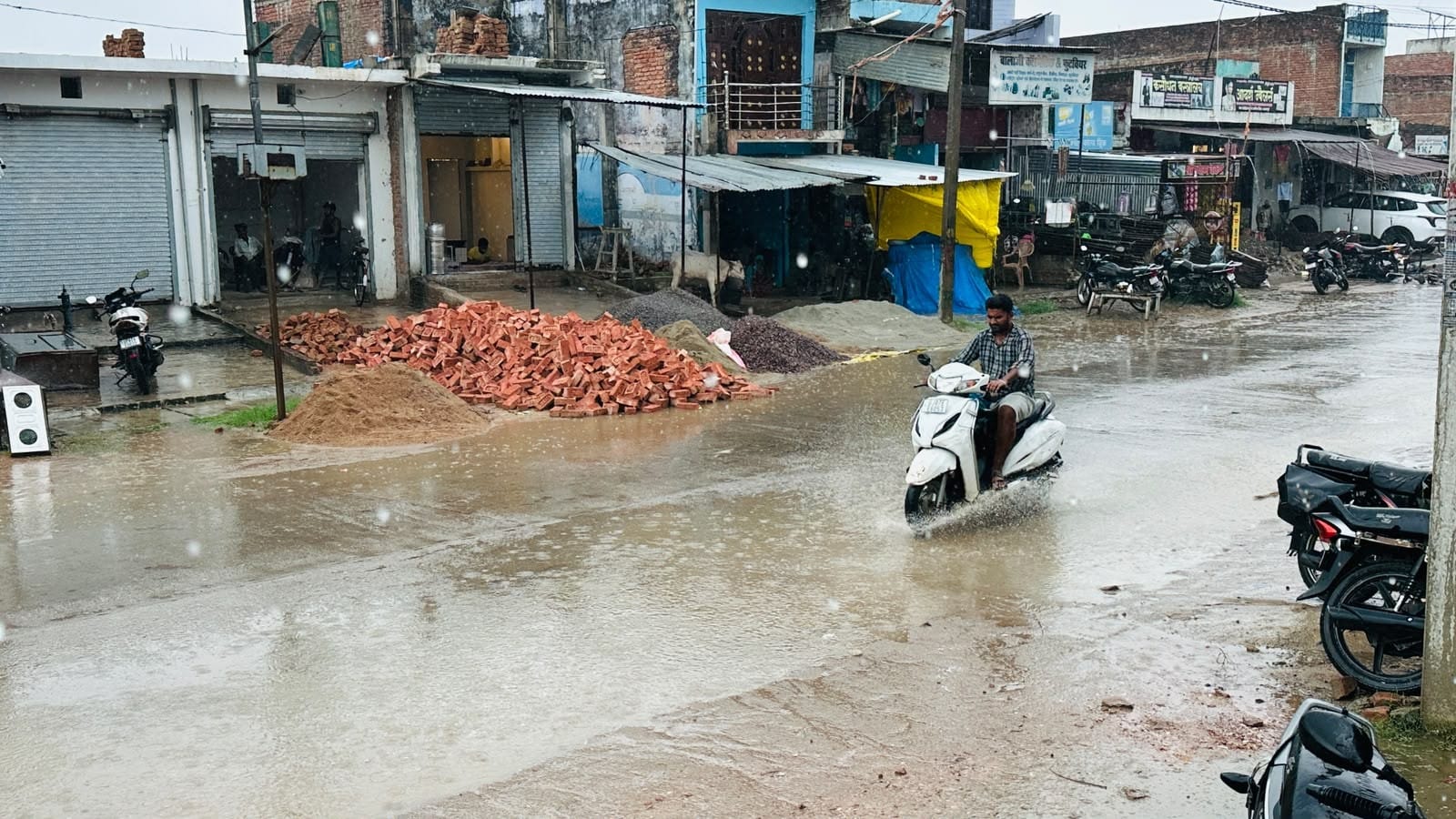 बलरामपुर के महदेइया बाजार में हो रही बारिश के बीच आवागमन कते लोग ।