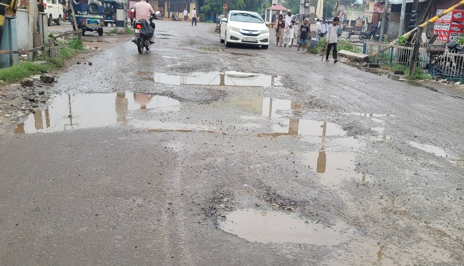नगीना में कोतवाली मार्ग पर रेलवे फाटक के करीब सड़क पर हुए गहरे गड्ढे। संवाद