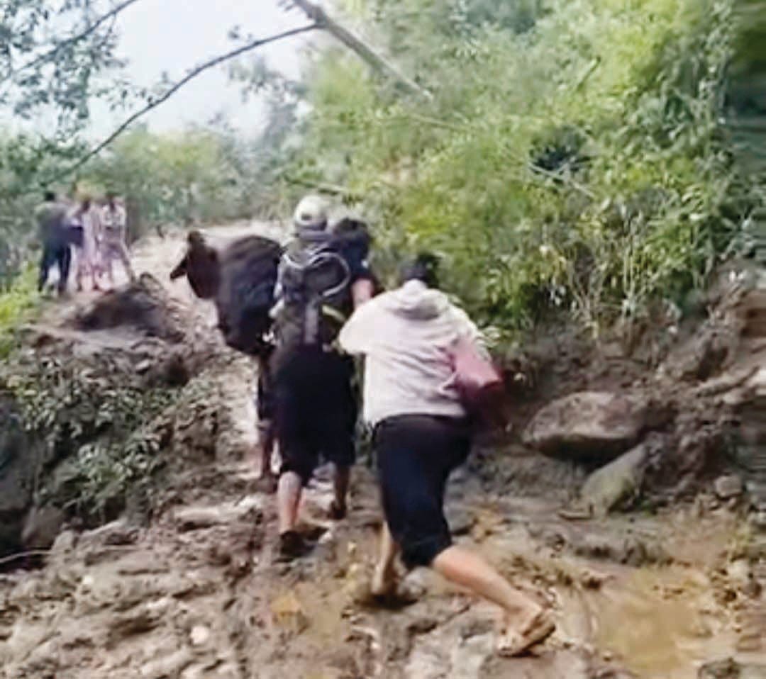 सैंज के शांघड में रोड बंद होने के कारण पैदल ही अपने गंतव्य की ओर जाते लोग