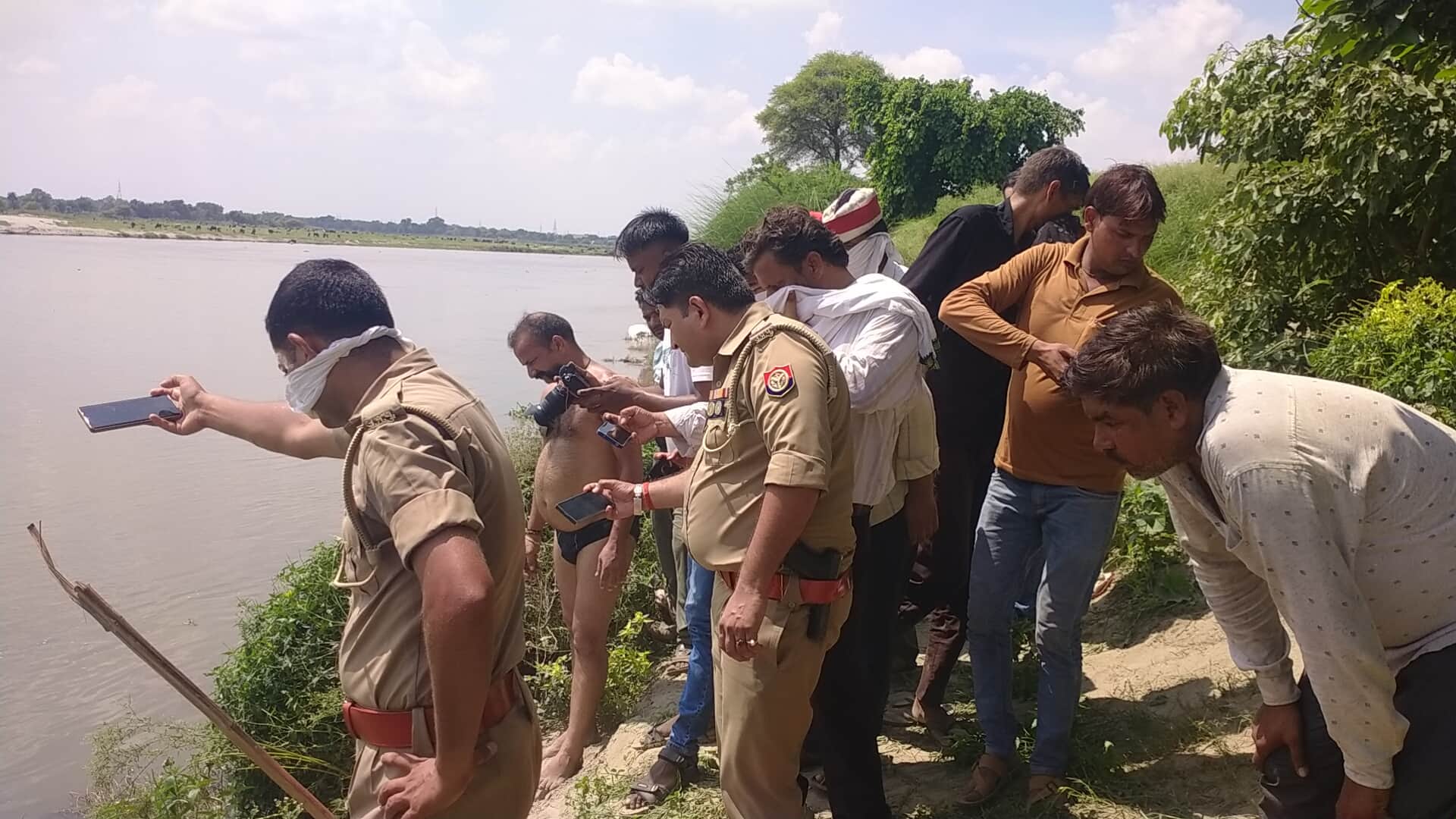 शव निकालते हुए परिजन व गोताखोर मौके पर टीम। 