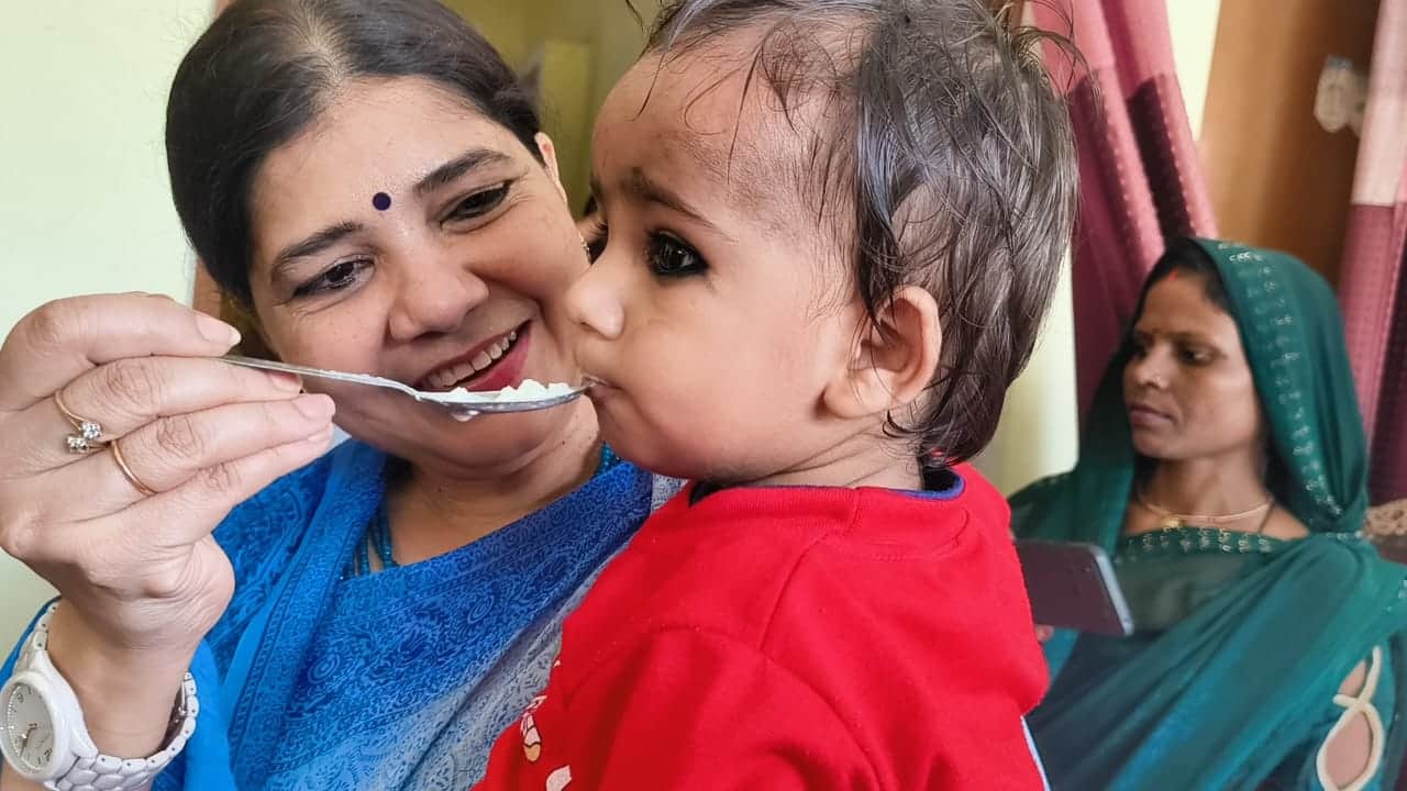 बच्चें का अन्नप्राशन करातीं उत्तर प्रदेश राज्य महिला आयोग की उपाध्यक्ष चारु चौधरी। स्रोत- सूचना