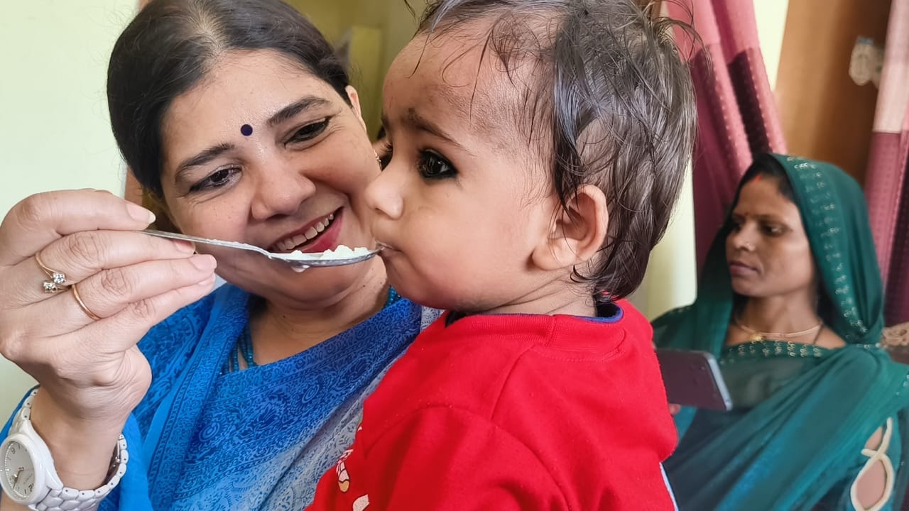 बच्चें का अन्नप्राशन करातीं उत्तर प्रदेश राज्य महिला आयोग की उपाध्यक्ष चारु चौधरी। स्रोत- सूचना