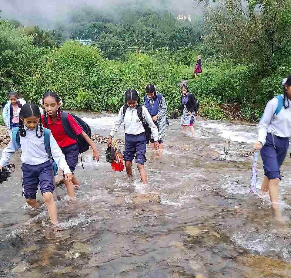 जान जोखिम में डालकर नदी पार करते स्कूली बच्चे।