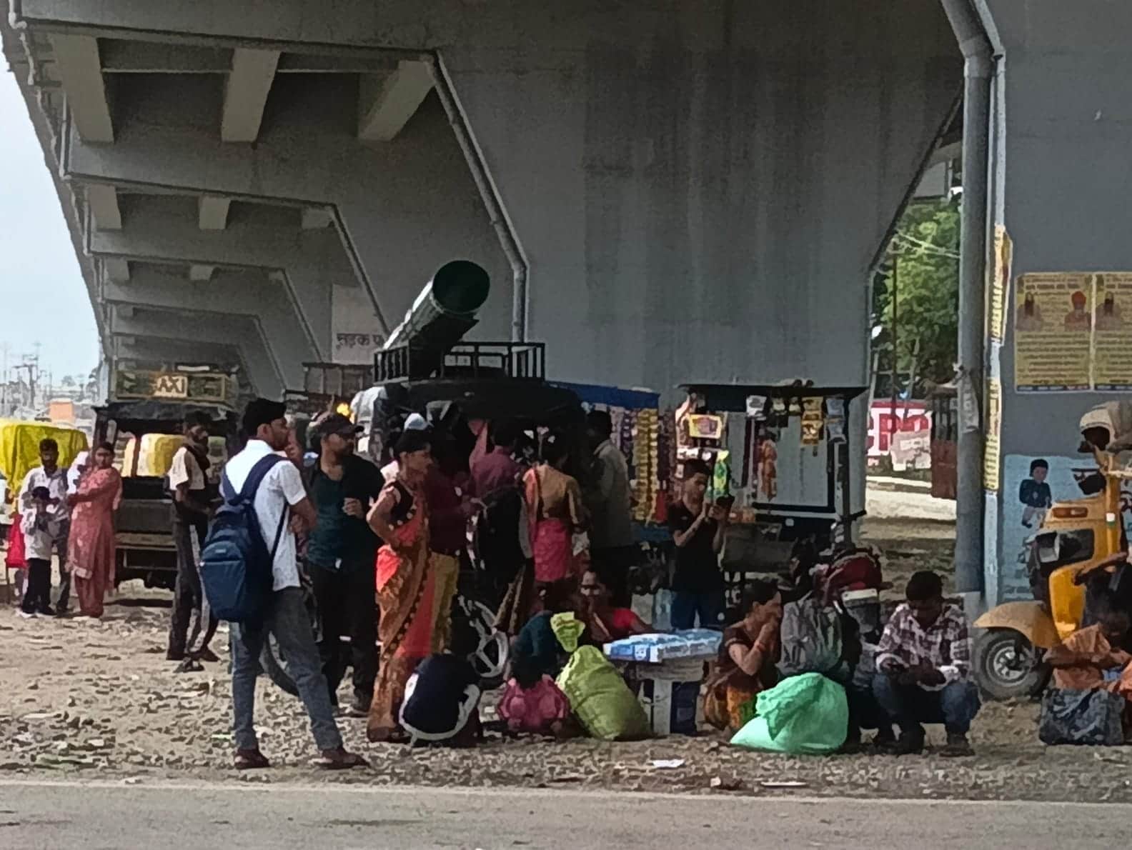 शहर के असम चौराहे पर फ्लाईओवर के नीचे खड़े यात्री। संवाद