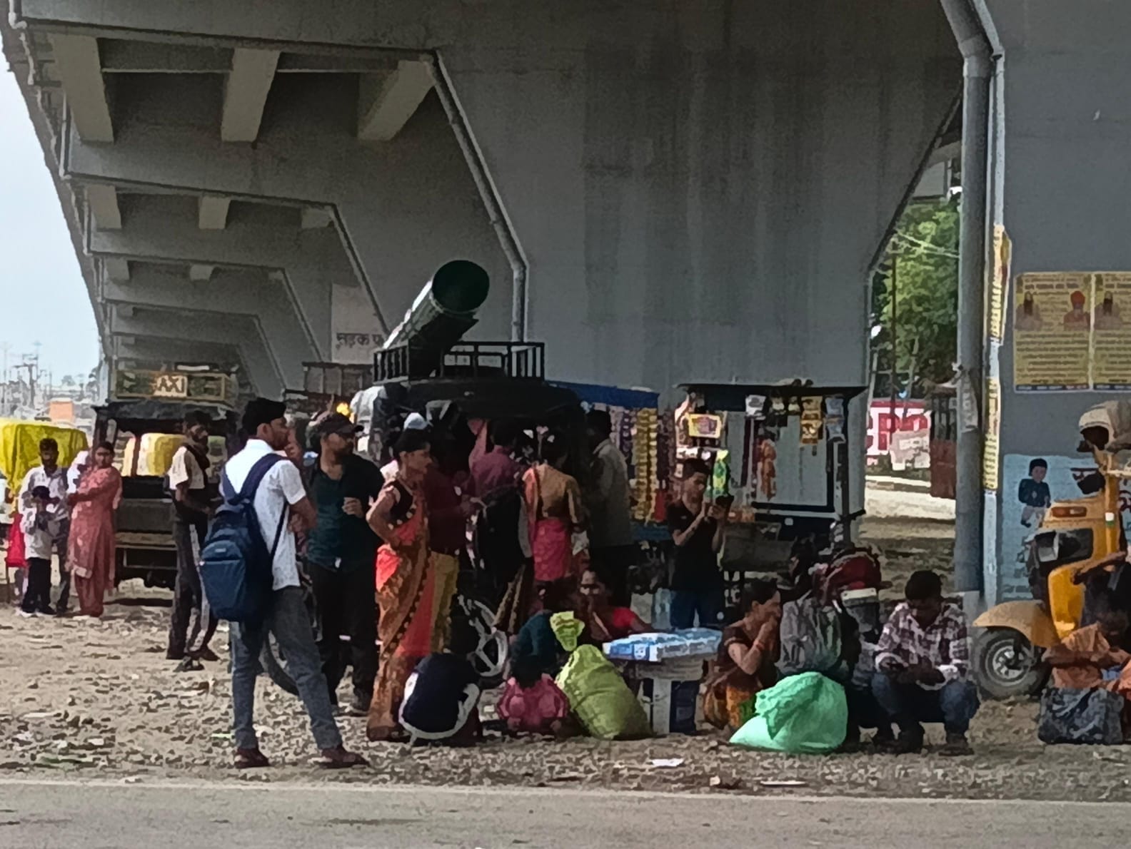 शहर के असम चौराहे पर फ्लाईओवर के नीचे खड़े यात्री। संवाद