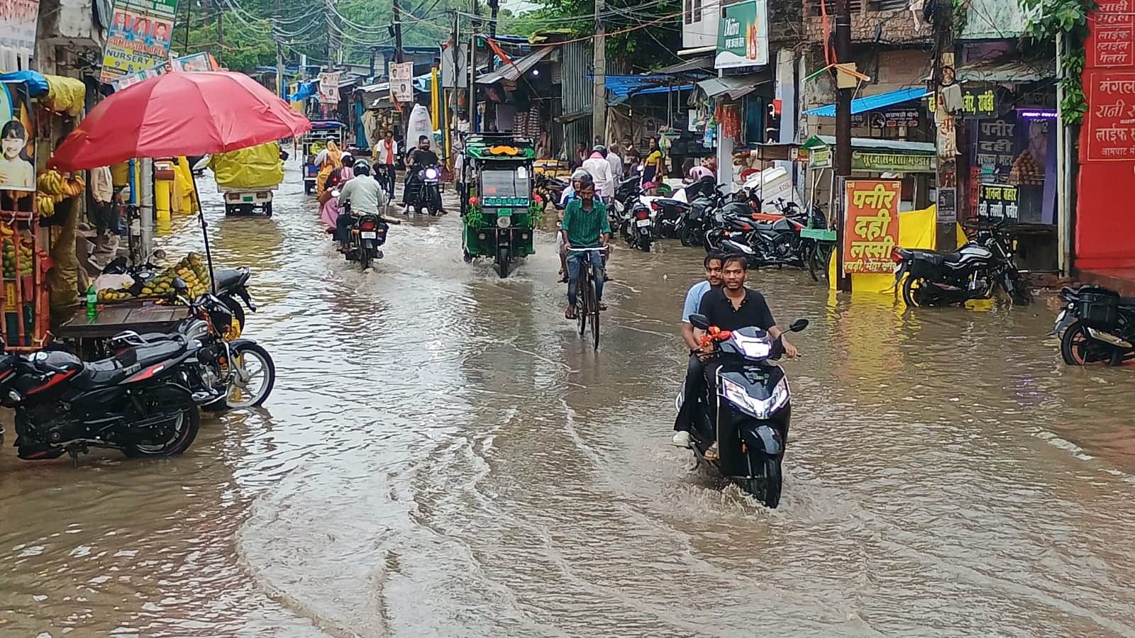 शहर के मिश्रबाजार में सड़क पर जलजमाव के बीच गुजरते बाइक सवार। संवाद
