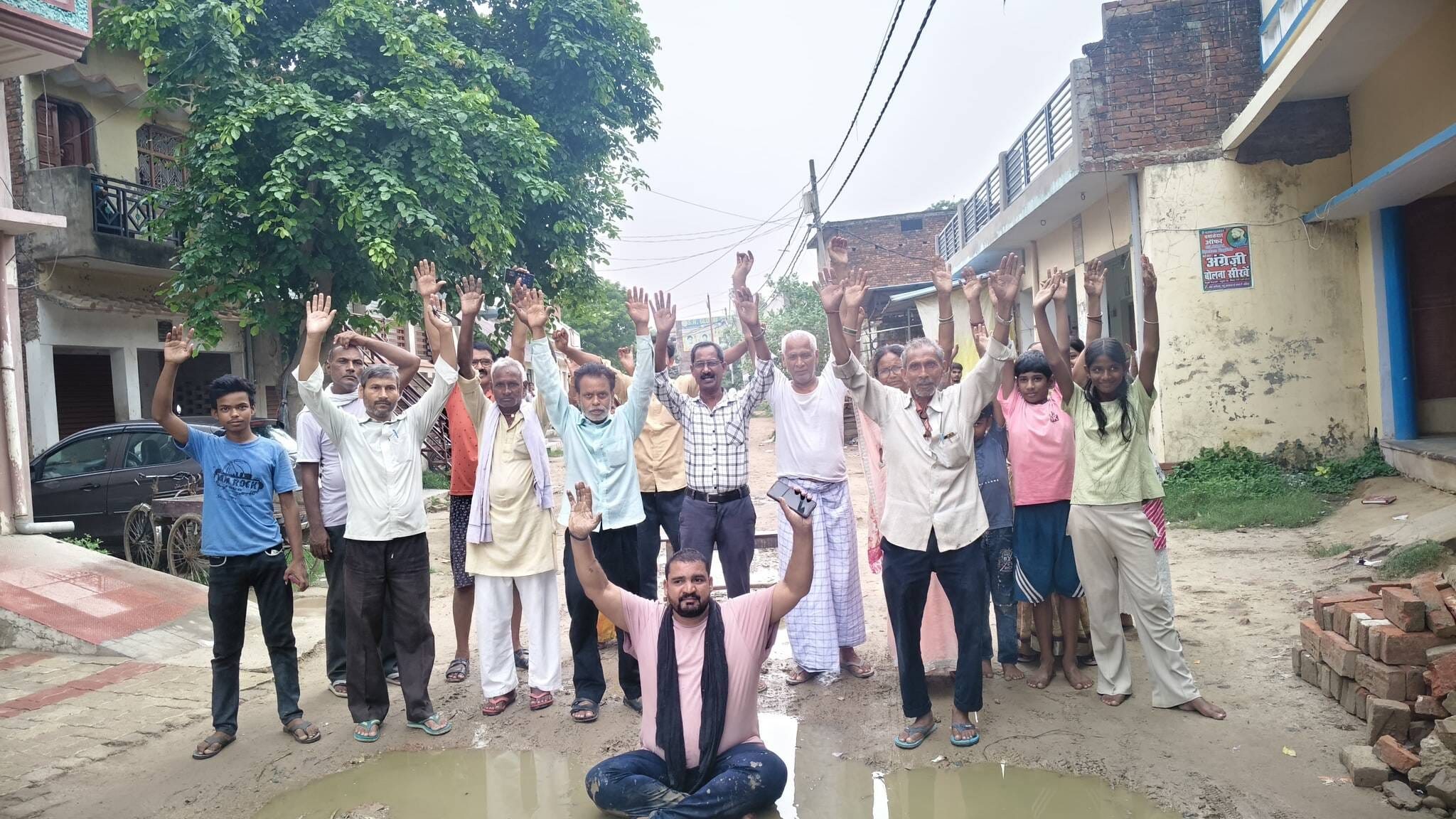 अमिला अम्बेडकर चौक के समीप जर्जर सड़क में जल जमाव में बैठकर प्रदर्शन करते ग्रामीण ।संवाद