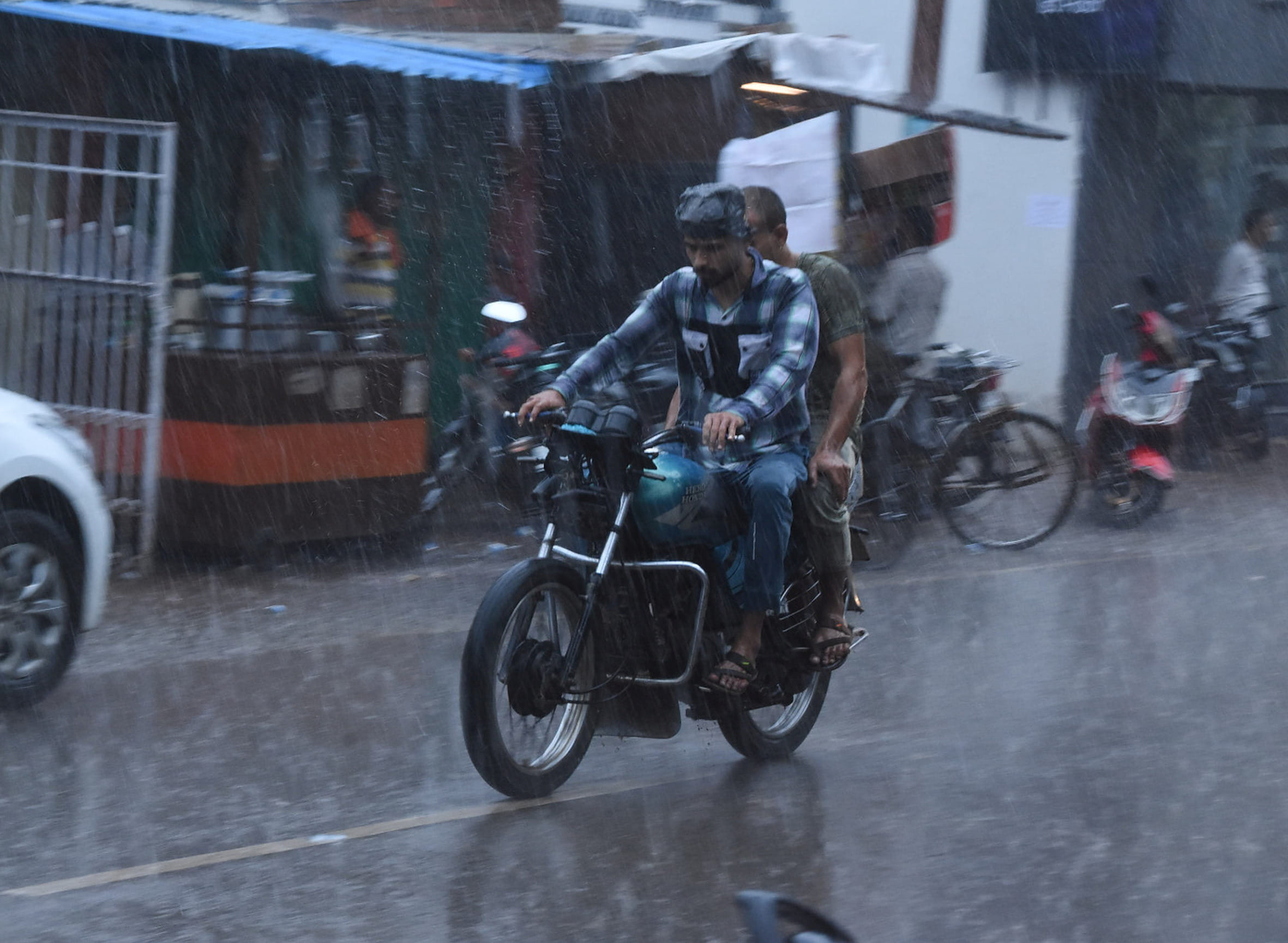 बहराइच में बारिश में भीगते हुए बाइक से जाते युवक।