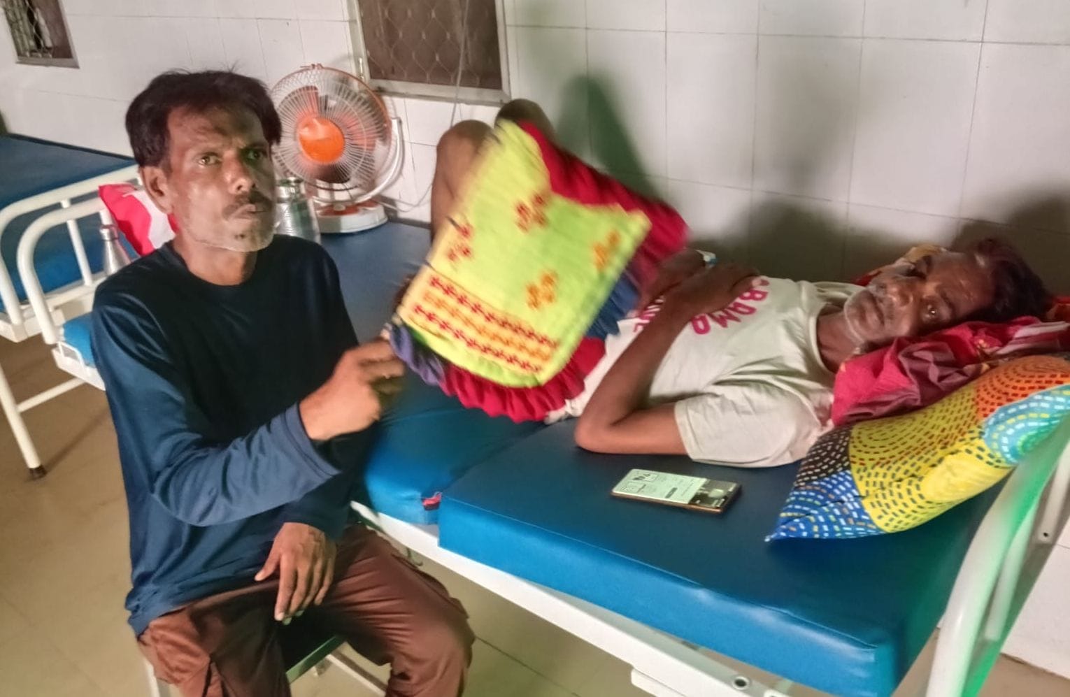 फोटो-13- मेडिकल कॉलेज के इमरजेंसी वार्ड में भर्ती मरीज पर हाथ से पंखा डुलता तीमारदार। संवाद
