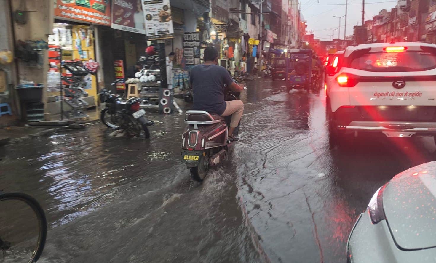 फोटो-26-शहर के बड़ा चौराहा के पास हुए जलभराव के बीच से निकलते वाहन। संवाद