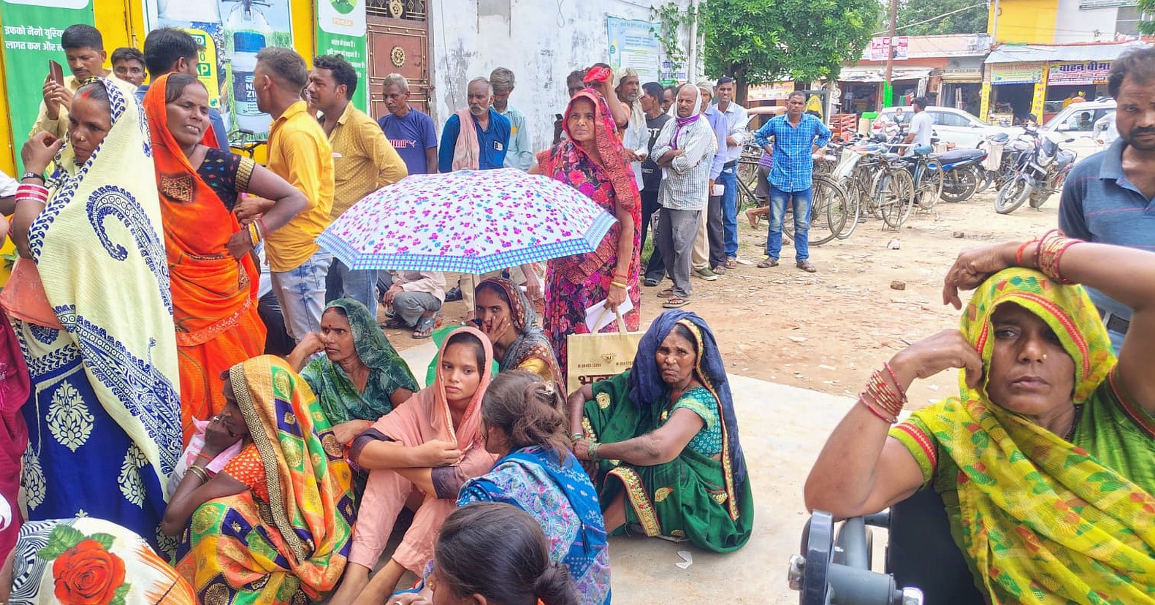 गौरीगंज इफको केंद्र पर खाद के इंतजार में धूप से बचाव के लिए छाता लगाकर बैठी महिला किसान। संवाद