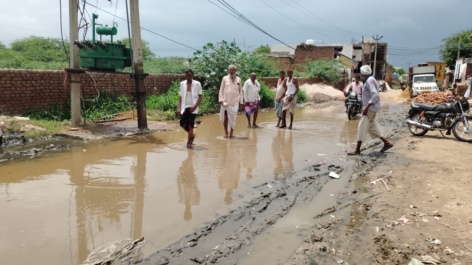मार्ग पर भरे गंदे पानी से होकर निकलते ग्रामीण।