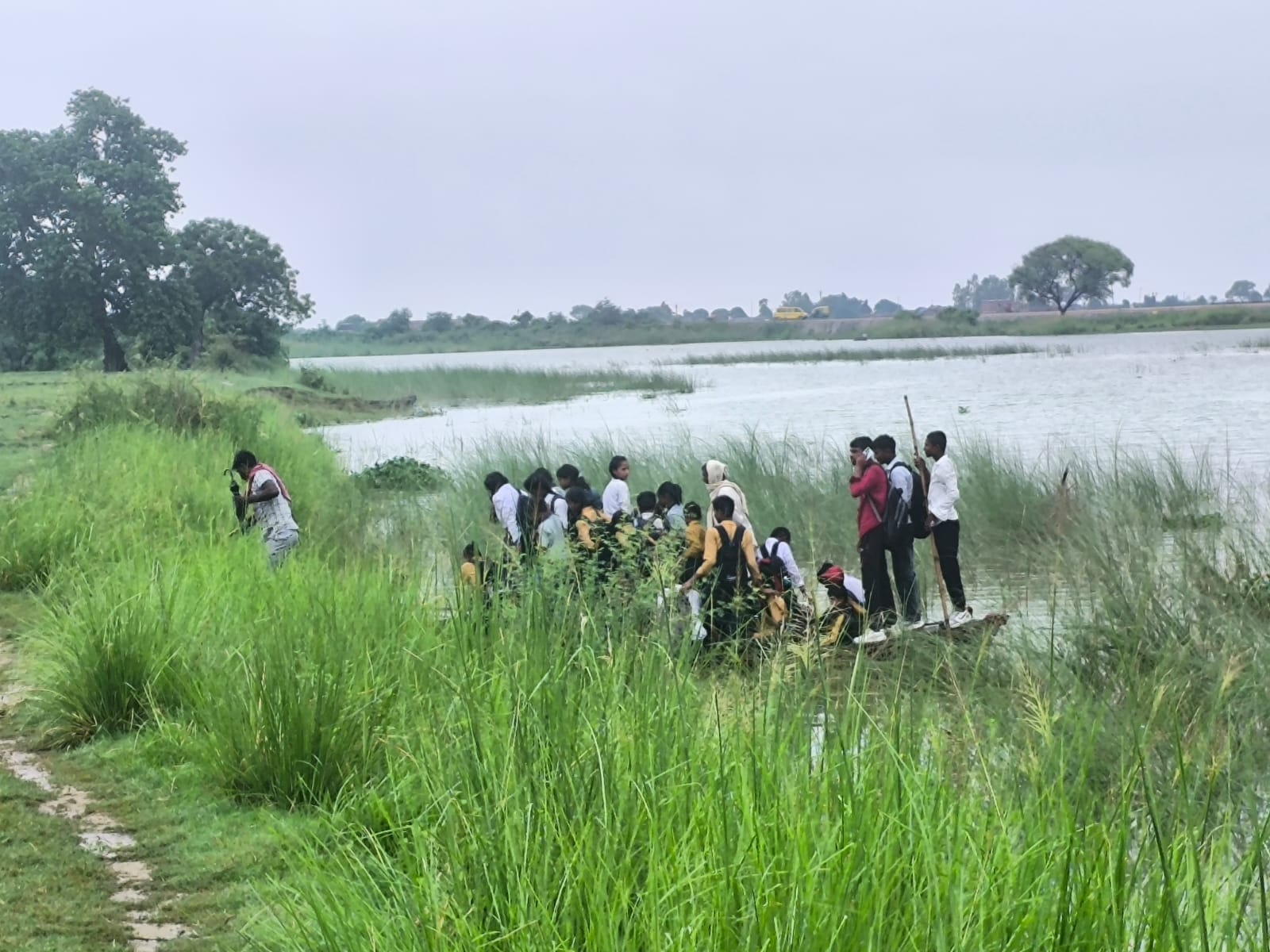 बरहज में नाव से आवाजाही करते राप्ती नदी से घिरे भदिला गांव के लोग 