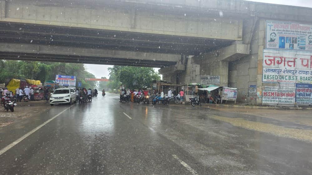 अकबरपुर टांडा मार्ग पर बृहस्पतिवार दोपहर बारिश के दौरान इनामीपुर फ्लाईओवर के नीचे इंतजार करते र