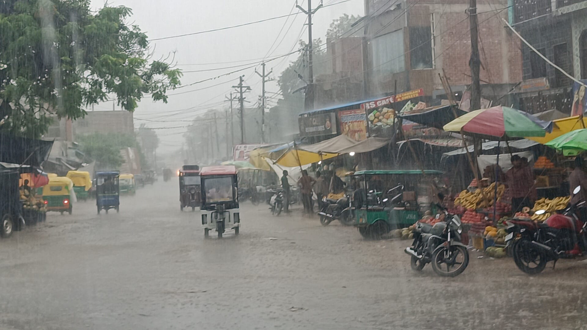 बिधूना कस्बे में बारिश के बीच निकलते वाहन। संवाद