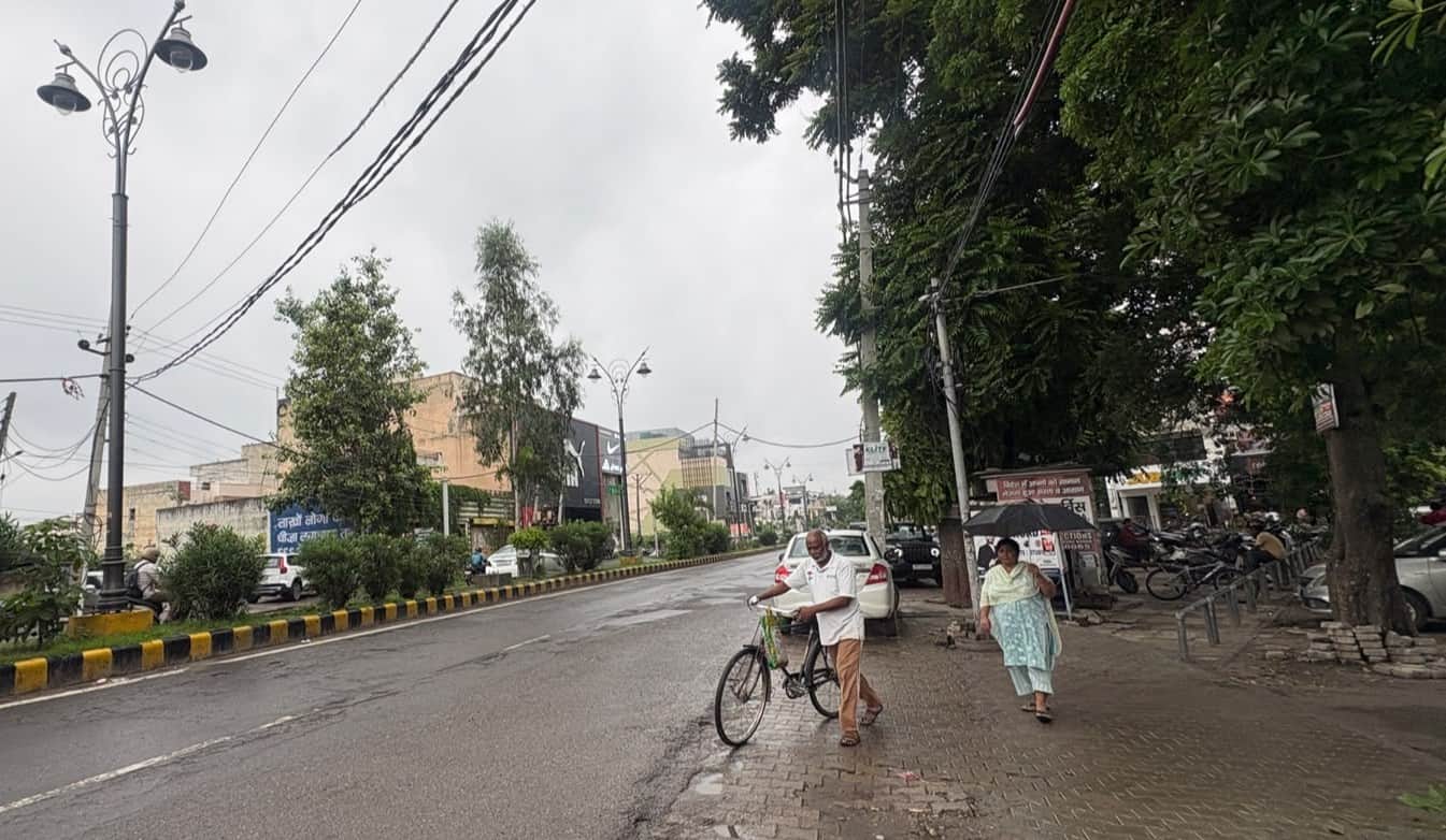 बूंदाबांदी के बीच मॉडल टाउन की गोबिंदपुरी रोड से गुजरते लोग। संवाद